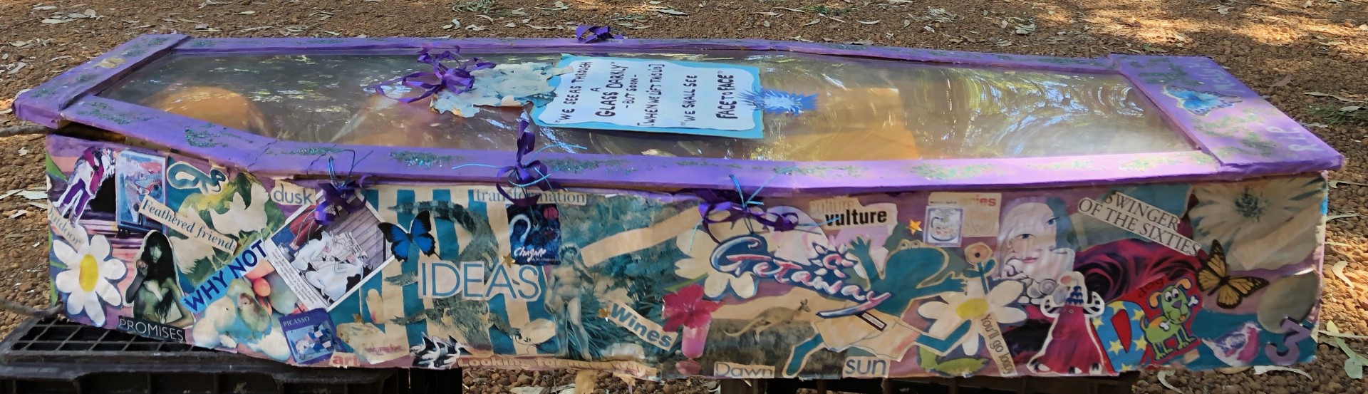 Colorful coffin with collage and a glass lid.